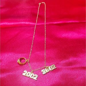 It is a neck chain, with a 2002 pendant and a ring, the material is gold,